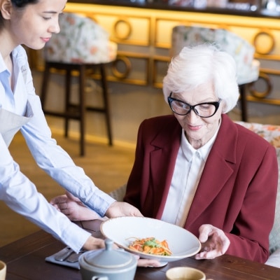 Elison Park | Senior woman receiving food from waitress